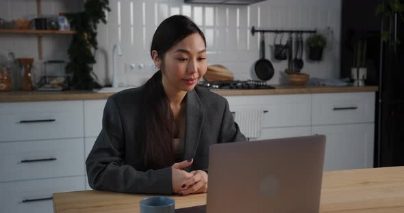 Asian Business Woman Making Business Video Call Meeting From Home Kitchen in the Evening on Holidays