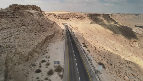 Black Car Driving on Asphalt Road Through the Desert Sands of the Blue Sky White Clouds in Israel