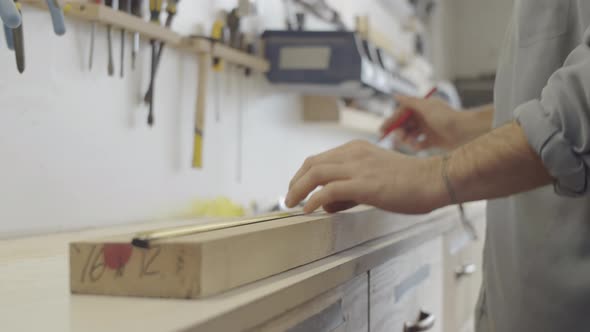 Skilled Carpenter Measuring and Marking Wood Board in Workshop alt