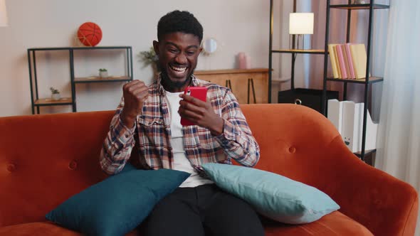 Young Adult Man at Home Use Mobile Cell Phone Typing Browsing Say Wow Yes Found Out Great Big Win alt
