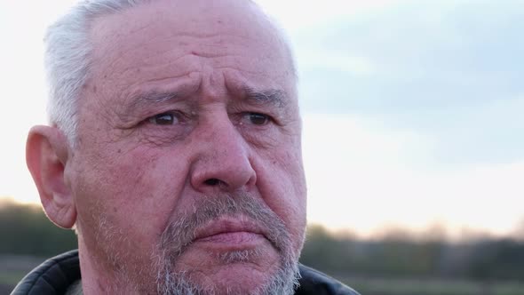 Closeup Portrait of a Bearded Gray Mature Man Pensively Sitting at Home in the Yard alt