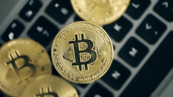 Golden Bitcoin Coins are Rotating on a Keyboard Background alt