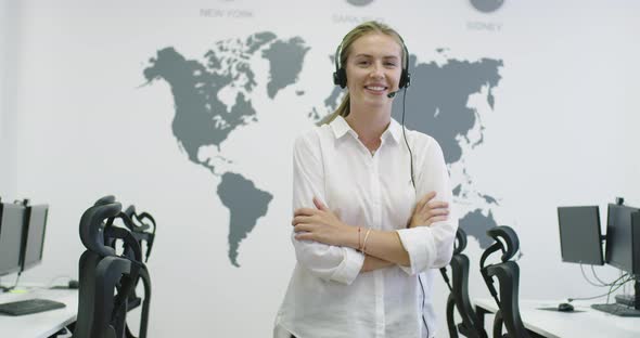 Beautiful Young Operator Woman Standing and Wearing Headset at the Bright Office Space alt