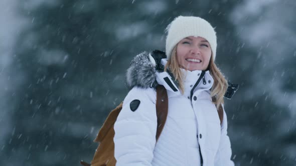 Smiling Caucasian Young Woman in Casual Winter Outfit Walking in Winter Forest alt