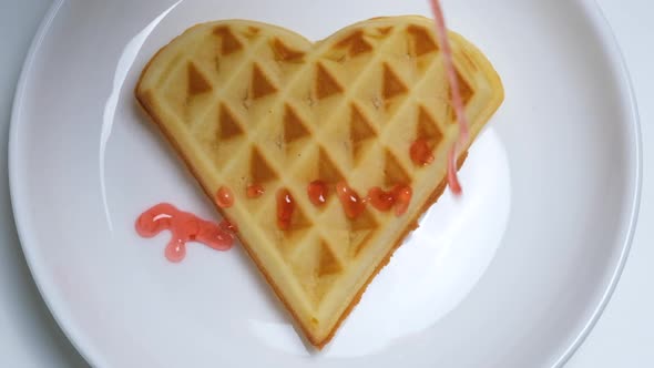 Close Up View on Home Made Heartshaped Waffle Topped with Strawberry Syrup