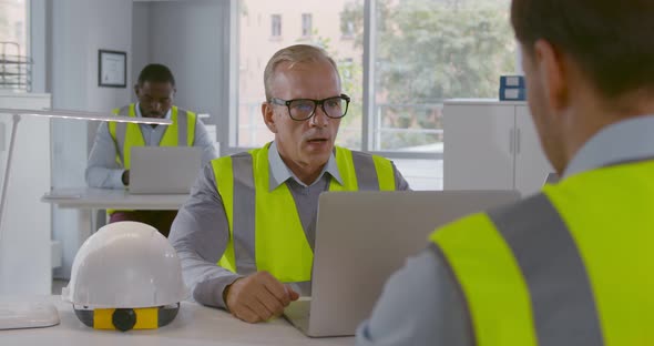 View Over Shoulder of Builder Talking to Foreman in Office alt
