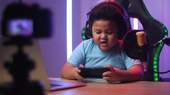 Excited Asian Little Boy Playing Video Game With Mobile Phone While Live Stream alt