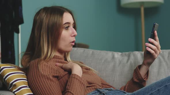 A Young Girl Is Lying on the Couch and Talking on a Video Call