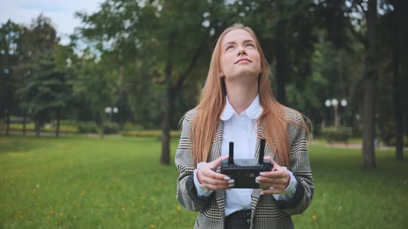 The Girl Controls the Drone with the Remote Control in Her Hands alt