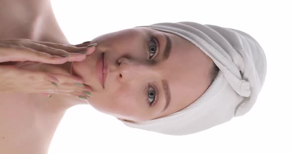 Portrait of a Young Caucasian Woman with a White Towel on Her Head Touching Her Cheeks Making a