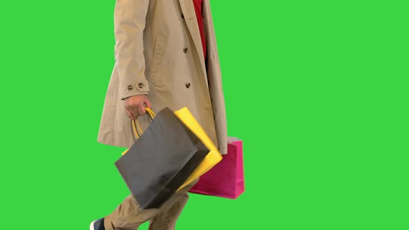 Shopping Bags in the Hands of Walking Man in a Coat on a Green Screen Chroma Key alt
