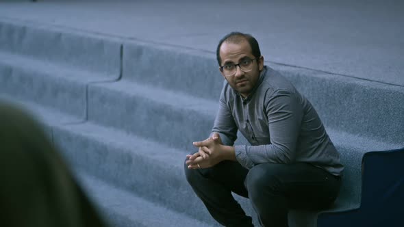 Two Men Communicating While Sitting Outside on Staircase alt