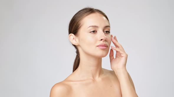 Beautiful Young Woman with Clean Fresh Skin Standing Over Light Grey Background alt
