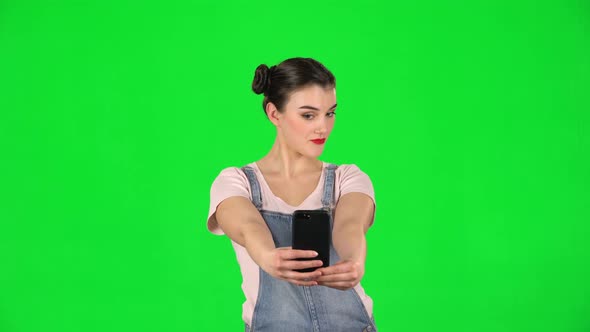 Girl Makes Selfie on Mobile Phone Then Looking Photos on Green Screen alt