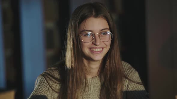 Happy Young Girl Rejoices and Hands Ups When Working with Laptop in Library alt