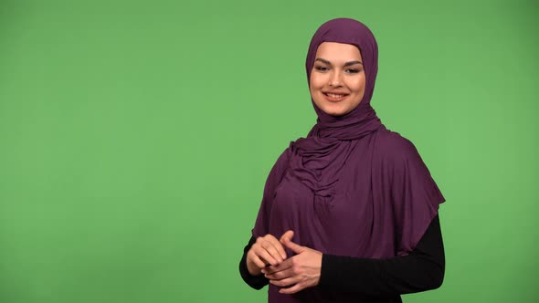 A Young Beautiful Muslim Woman Waves at the Camera with a Smile  Green Screen Background