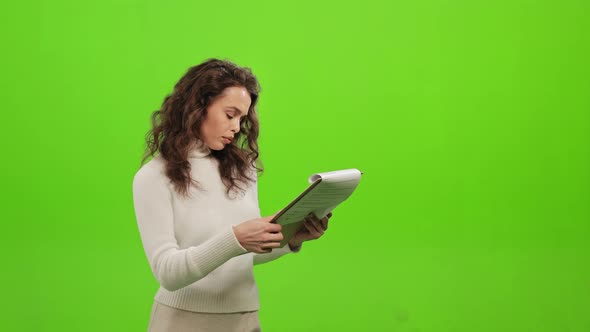 The Woman is Flipping Through the Documents and Searching for the Necessary Information