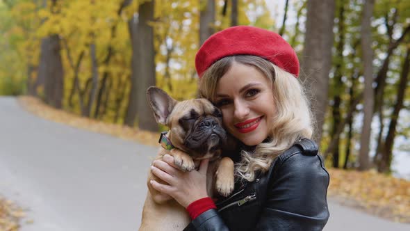 Portrait of a Smiling Happy Cheerful Woman with Funny French Bulldog in Autumn Park alt