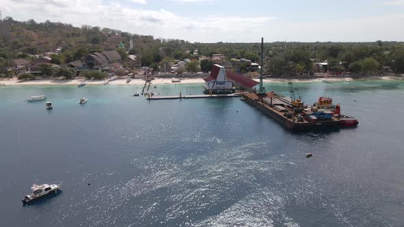Aerial circling shot of platform ferry loading cargo freight at pier of GIli Trawangan,Indonesia. alt
