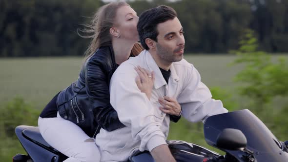 Beautiful Couple Rides Sport Motorcycle on the Road Near Summer Field