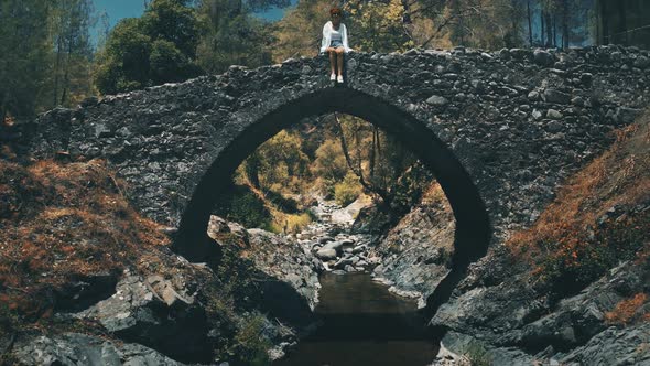 Woman Traveler Tourist Sit on Ancient Stone Old Bridge Explore Medieval Historical Architecture