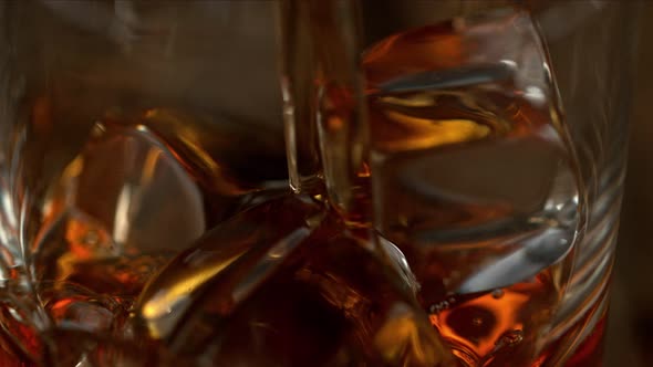 Super Slow Motion Macro Shot of Pouring Whiskey Into Glass with Ice Cubes with Camera Movement alt