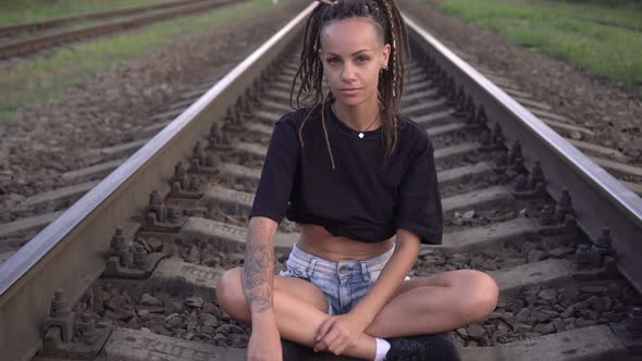 Young Sexy Modern Woman Sits on Rails and Sleepers on the Railroad alt