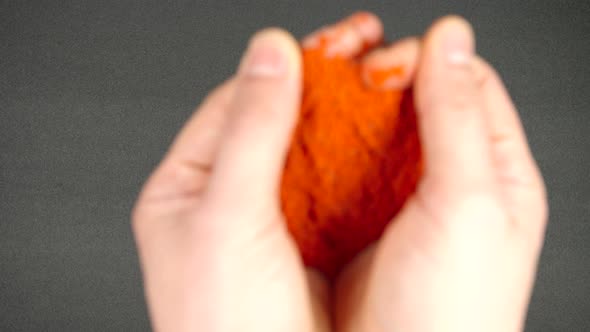 Human hands throw a red pepper powder on a black table