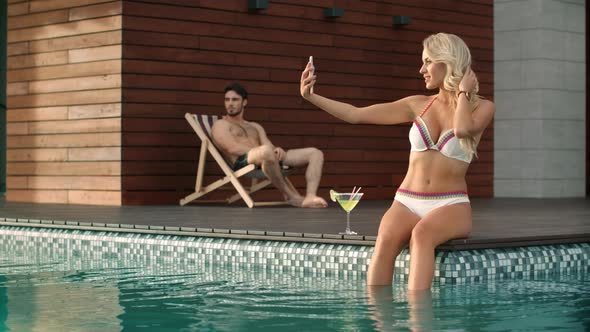Slim Woman Taking Selfie Photo in Swimming Pool at Luxury House alt