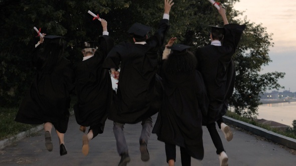 Five young graduates jump up while walking alt