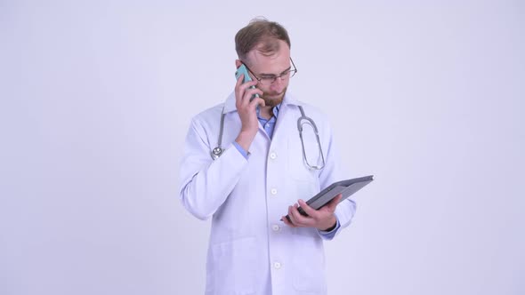 Happy Bearded Man Doctor Talking on the Phone While Using Digital Tablet