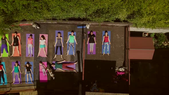 Aerial view of a group of people doing yoga on a terrace surrounded by trees. alt