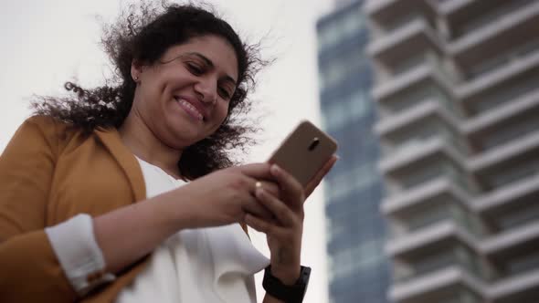 Smiling Young Businesswoman Relaxing on Work Break Texting on Smartphone alt