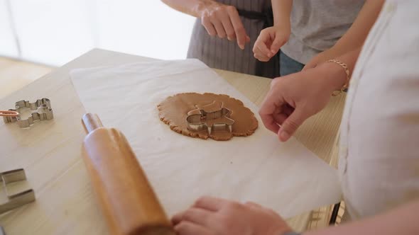 Little Boy Cutting Biscuits Out of Dough in Kitchen with Parents alt