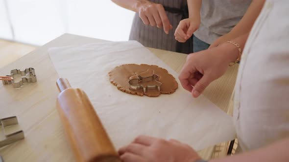 Little Boy Cutting Biscuits Out of Dough in Kitchen with Parents
