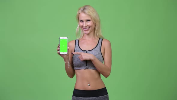 Young Happy Beautiful Woman Showing Phone and Giving Thumbs Up Ready for Gym