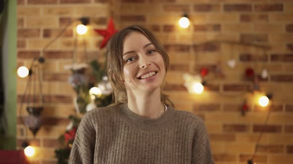 Portrait of Pretty Adult Girl Standing at Home with Christmas Decoration on Background alt