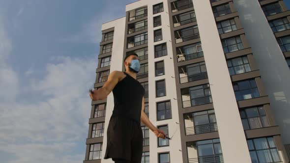 A Young Man of Athletic Build Jumps on a Skipping Rope in a Medical Mask alt