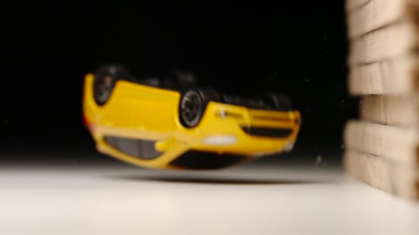 Yellow toy car bumps into a wall and turns over