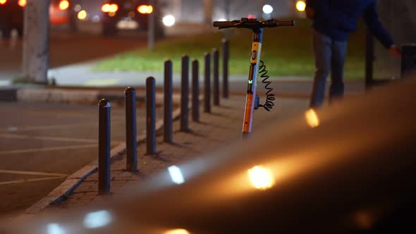 The Electric Scooter is Parked Near the Roadway at Night