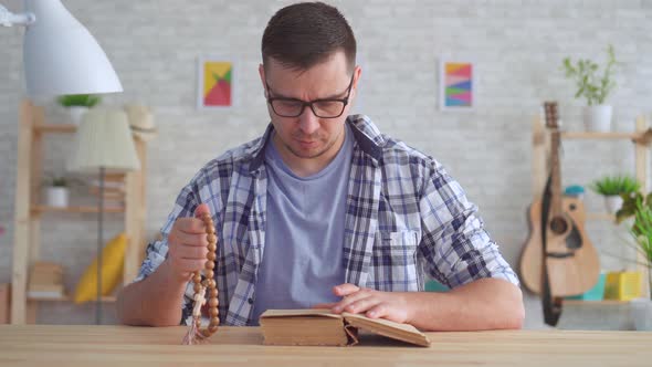 Portrait Young Man with Glasses with a Rosary in His Hands and Reading the Bible alt