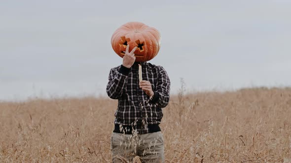 A Man with a Halloween Pumpkin on His Head and with Candles in His Hand Threatens the Camera alt