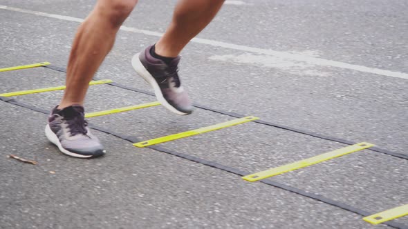 Close-up legs sportsman training with agility ladder equipment.