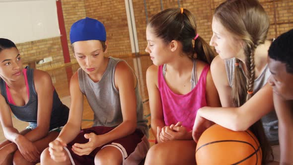 High school kids sitting on a bench in basketball court alt