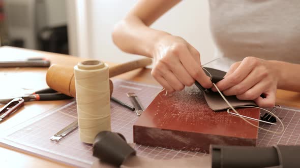 Woman sewing leather at home