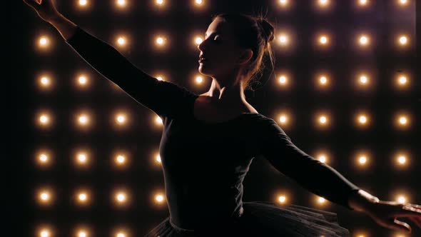 Silhouette of Ballerina in Black Dress Is Dancing Ballet in the Dark Studio