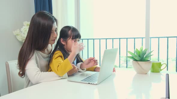 Asian single mother teaching homework to her little sibling daughter child