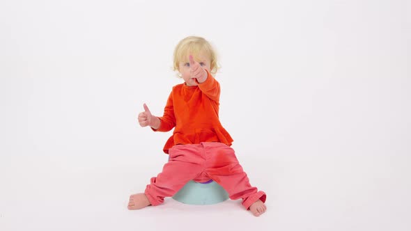 Adorable Happy Cheerful Toddler Girl Sitting on Potty Showing Thumbs Up Gesture