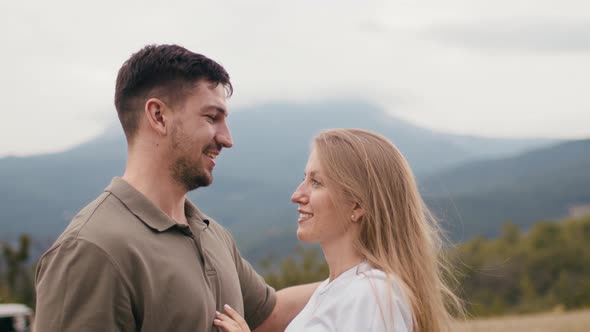 Young Loving Couple Standing and Hugging in Mountains