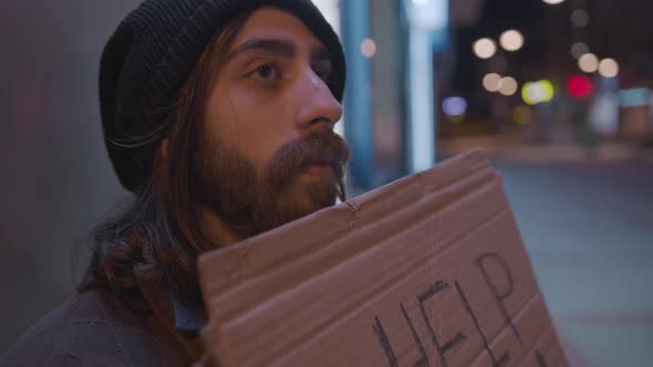Homeless long haired bearded young beggar man waiting for help